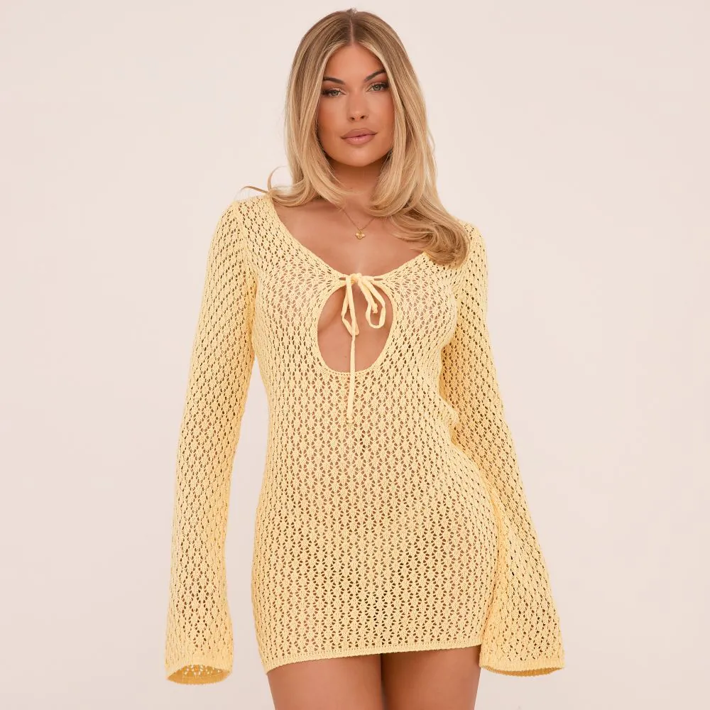 a yellow crochet mini dress with tie front detail and a neckline cut out. The crochet dress is a bodycon fit with long flared sleeves. 